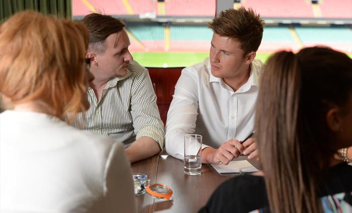 Four people having a business meeting around a conference table at Principality Stadium Cardiff.
